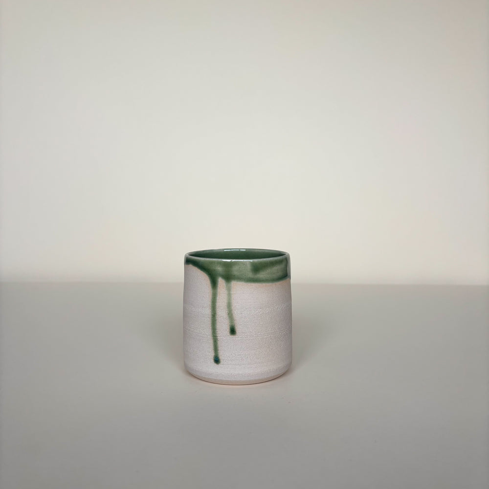 Ceramic cup raw clay texture outside with green accent on a plain cream background. Pottery tumbler  Handmade in Ireland. Wheel Thrown Pottery and Ceramic. 