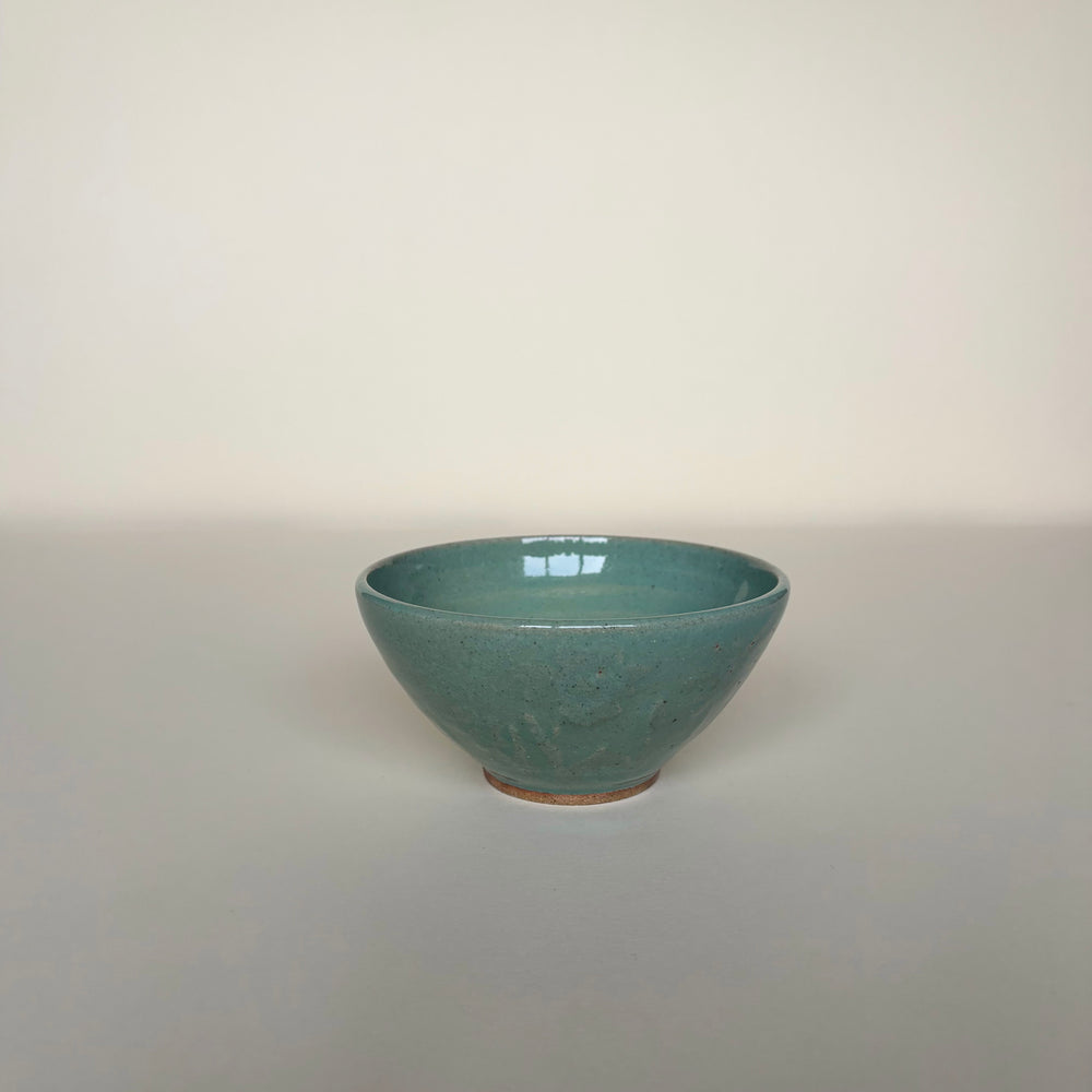 Green ceramic bowl on a cream background. Green Pottery bowl  Handmade in Ireland. Wheel Thrown Pottery and Ceramic. 
