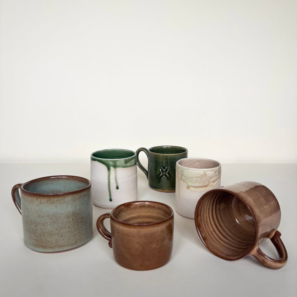 Set of ceramic mugs with various designs on a cream background. Pottery Mugs Handmade in Ireland. Wheel Thrown Pottery and Ceramic. 