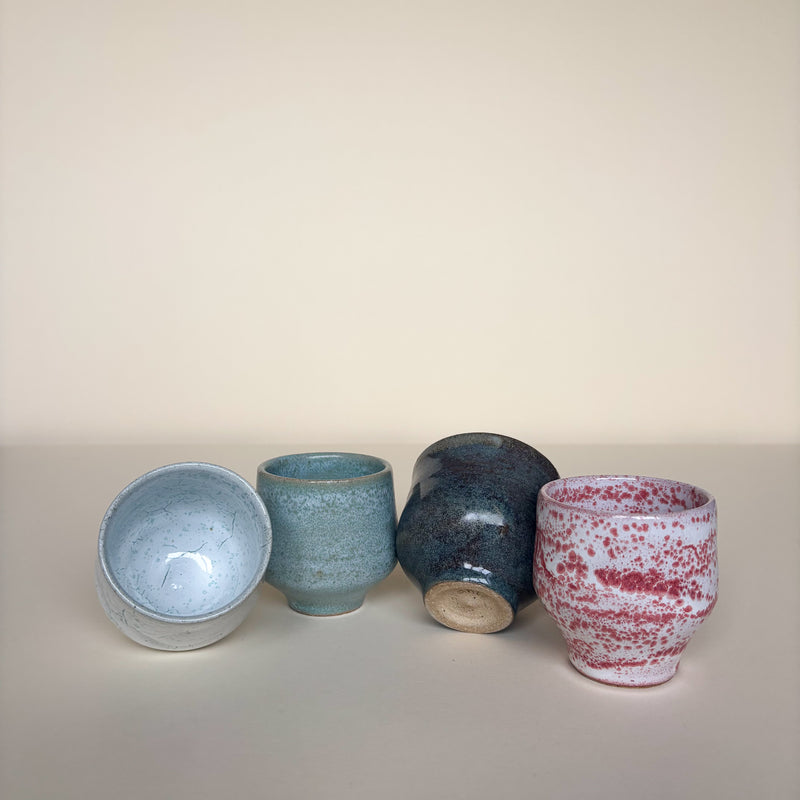 Four ceramic vessels with different textures and colors on a cream background. Pottery shot cups, spirit cups, wine cup Handmade in Ireland. Wheel Thrown Pottery and Ceramic. Stephanie Garrigan Ceramic Set of ceramic  cups with same form and various colours. 