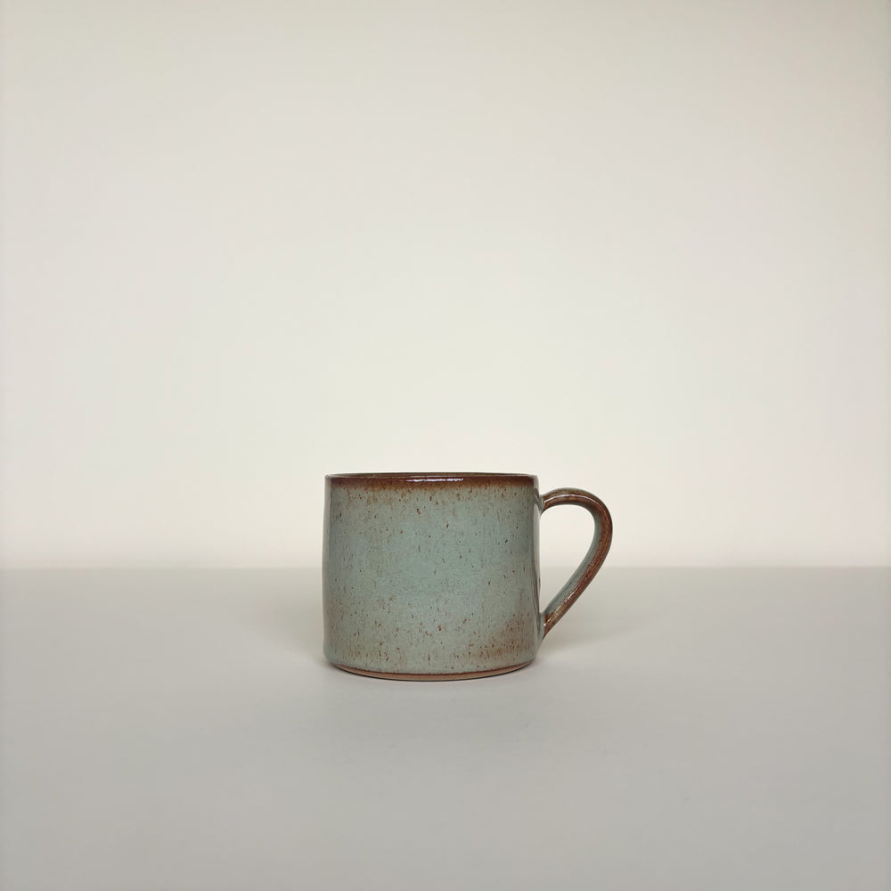 Green Ceramic mug with  brown speckles pattern on a cream background. Pottery Mug Handmade in Ireland. Wheel Thrown Pottery and Ceramic. 