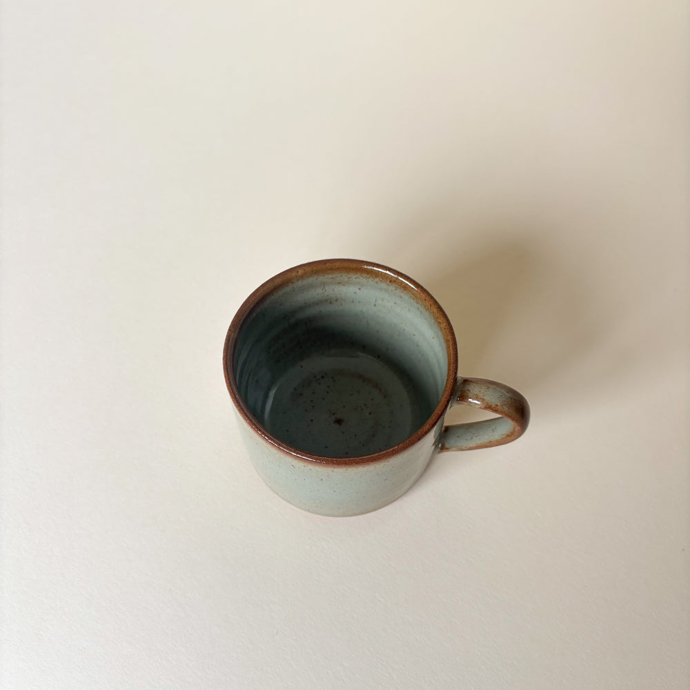 Green Ceramic mug with a handle on a plain background. Pottery Mug Handmade in Ireland. Wheel Thrown Pottery and Ceramic. 