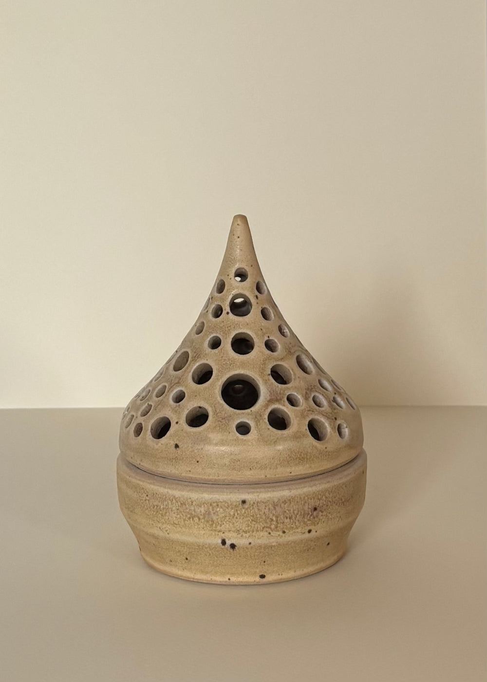 Light Cream coloured ceramic tea light candle holder with carved dots design on a light beige  background. Pottery  Handmade in Ireland. Wheel Thrown Pottery and Ceramic. 