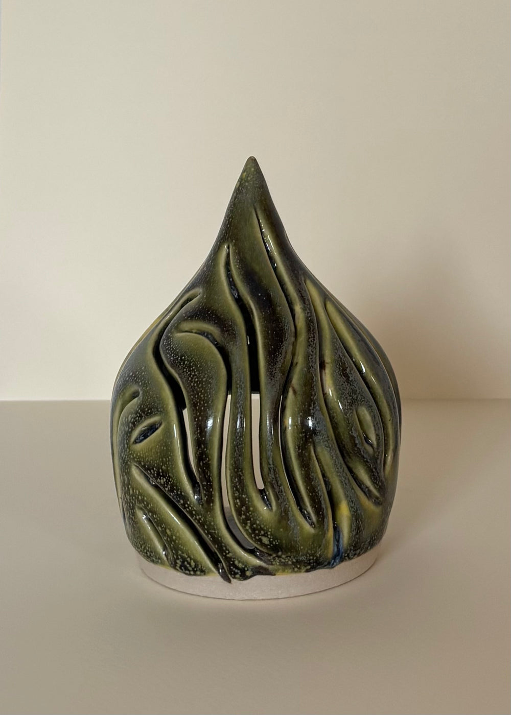 Green ceramic tea light candle holder with carved wavy design on a light beige  background. Pottery  Handmade in Ireland. Wheel Thrown Pottery and Ceramic.