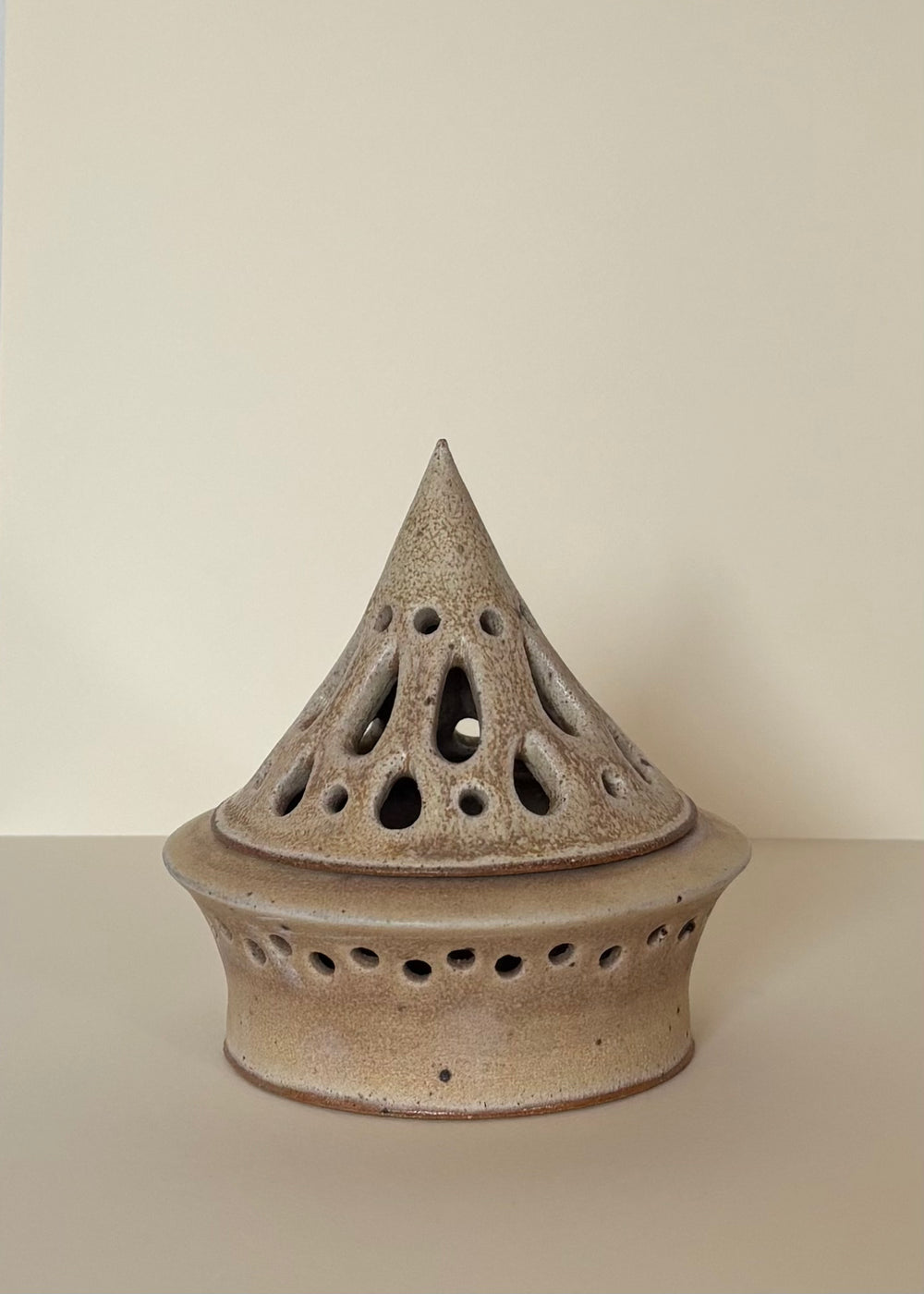 Light Cream coloured ceramic tea light candle holder with carved droplets design on a light beige  background. Pottery  Handmade in Ireland. Wheel Thrown Pottery and Ceramic. 