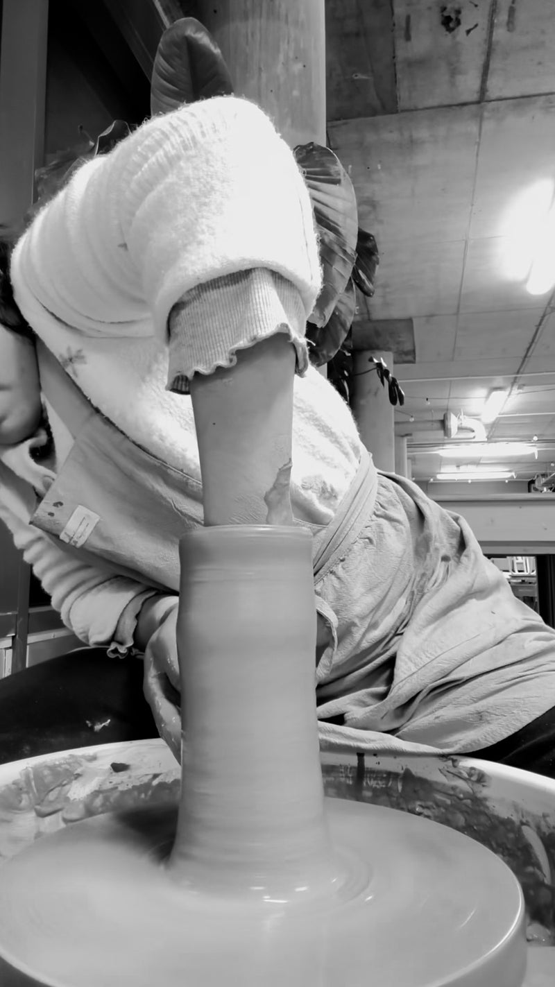 Person working with clay on a pottery wheel in a workshop.