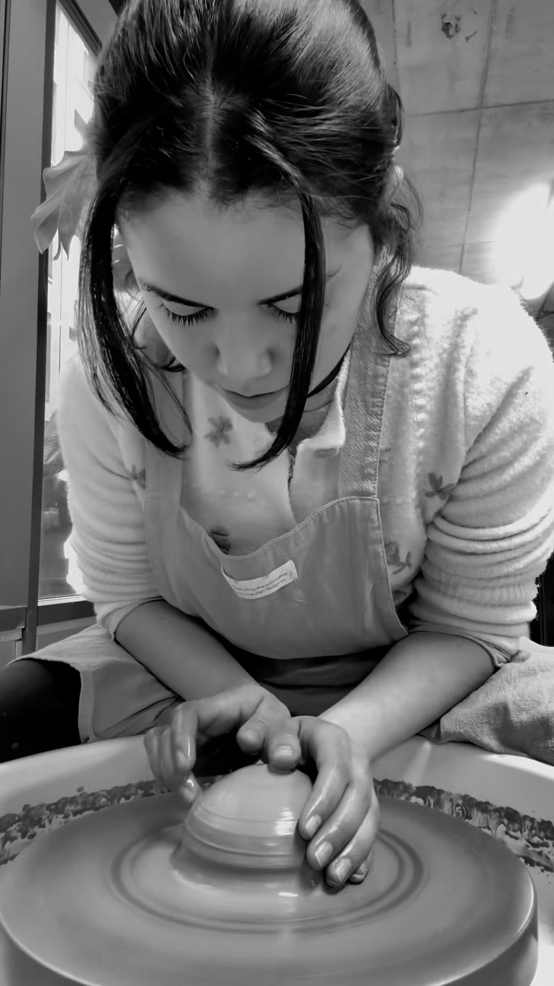 Stephanie Garrigan working with clay on a pottery wheel in a studio setting